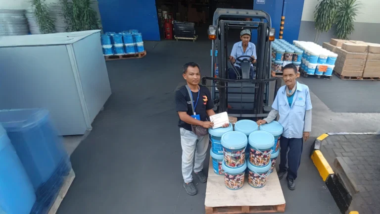 Tim Tiga Logistik menyerahkan kiriman cat di gudang pelanggan